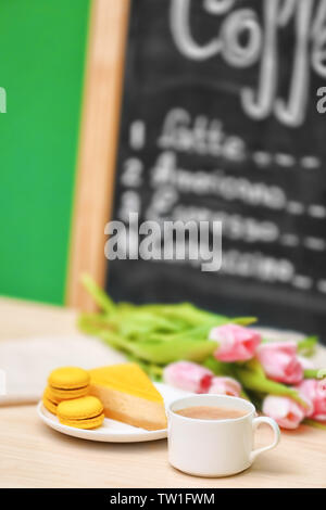 Tasse Kaffee, leckeren Kuchen und Schönen Blumenstrauß auf dem Tisch im Cafe Stockfoto