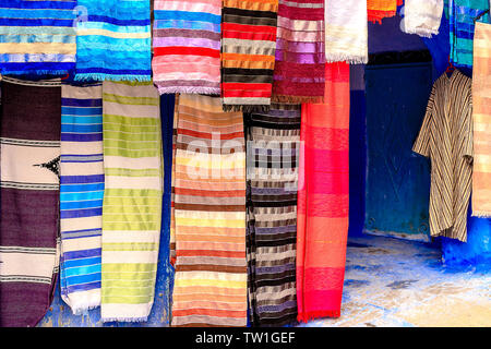 CHEFCHAOUEN, MAROKKO - April 24, 2019: Bunte marokkanische Stoffen und handgefertigte Souvenirs auf der Straße in die blaue Stadt Chefchaouen, Marokko, Afrika. Stockfoto