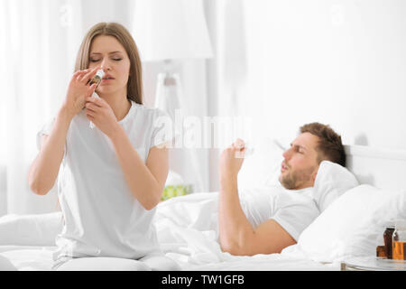 Junge Frau die nasale Tropfen auf dem Bett zu Hause. Stockfoto