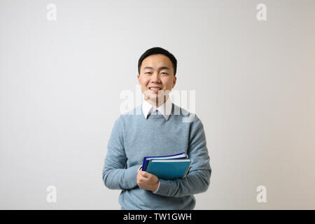 Gutaussehenden jungen asiatischen Lehrer auf hellen Hintergrund Stockfoto