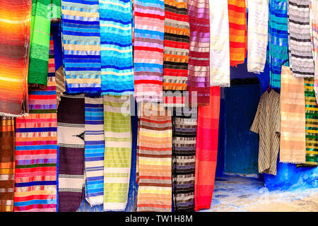 CHEFCHAOUEN, MAROKKO - April 24, 2019: Bunte marokkanische Stoffen und handgefertigte Souvenirs auf der Straße in die blaue Stadt Chefchaouen, Marokko, Afrika. Stockfoto