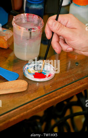 Mann Maler ist das Mischen von Farben vor dem malerei Kunst lack Studio. Künstler in seiner Hand hält Pinsel Farbe Ölfarben für Malerei auf der Palette gemischt. Stockfoto