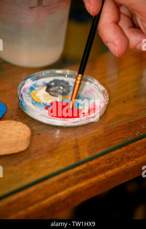 Mann Maler ist das Mischen von Farben vor dem malerei Kunst lack Studio. Künstler in seiner Hand hält Pinsel Farbe Ölfarben für Malerei auf der Palette gemischt. Stockfoto