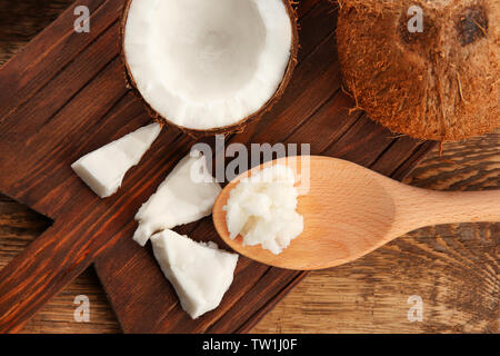 Kokosnuss und Löffel mit frischem Öl auf Holzplatte Stockfoto