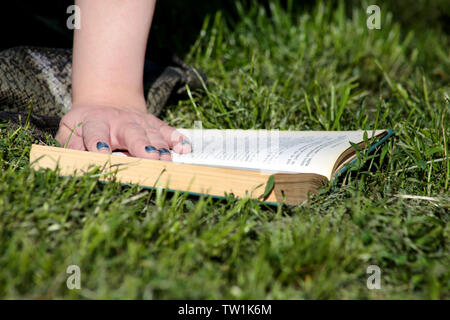 Schön mode Frau liegt auf grünem Gras und Lesen eines interessanten Buches, im Stadtpark, am Sommer, der Tag. Gut aussehender student Frau sitzt und liest. Stockfoto