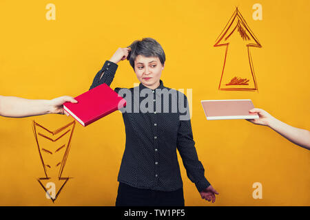 Nachdenklich Studentin denkt, was zwischen einem Lehrbuch und e-Book zu wählen. Traditionelle vs moderne Ausbildung. Zweifelnd Reader machen Wahl für Technolo Stockfoto