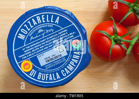 Packung Mozzarella di Bufala Campana Mozzarella mit strauchtomaten auf Holzbrett Stockfoto