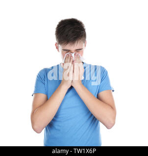 Junger Mann blasen Nase auf Gewebe vor weißem Hintergrund Stockfoto