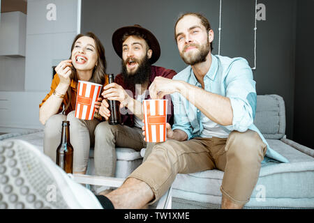 Junge Freunde gerade einige Film, sitzen zusammen mit Pop cornes auf der Couch zu Hause Stockfoto