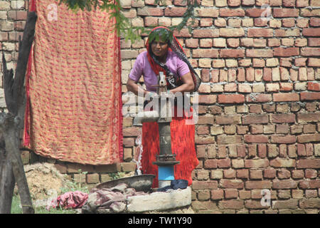 Frau Zeichnung Wasser aus einer Wasserpumpe, Indien Stockfoto