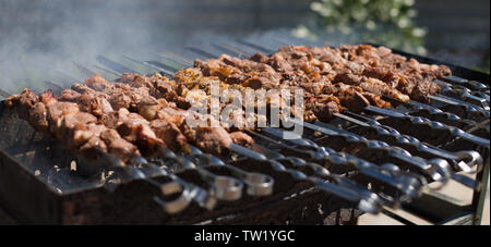 Schaschlik oder shashlyk Vorbereitung auf einem Grill über Kohle. Gegrillte Cubes von Schweinefleisch auf Metall Spieß. Fleisch am Spieß geröstet wird in Brand. Stockfoto