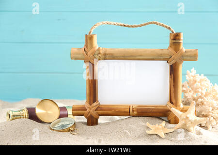 Bambus Rahmen mit Platz für Text und Reisezubehör auf Sand gegen Farbe Hintergrund Stockfoto