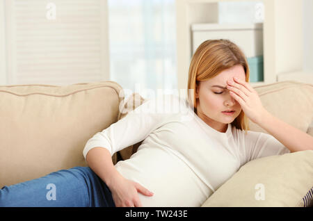 Schwangere Frau leidet unter Kopfschmerzen beim Liegen auf dem Sofa zu Hause Stockfoto
