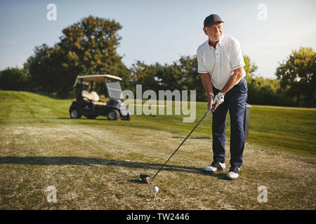 Sportliche älterer Mann über einen Schuss mit seinem Treiber machen, während Sie eine Runde Golf auf einem sonnigen Tag Stockfoto