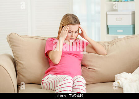 Schwangere Frau leidet unter Kopfschmerzen beim Sitzen auf dem Sofa zu Hause Stockfoto
