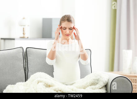 Schwangere Frau leidet unter Kopfschmerzen beim Sitzen auf dem Sofa zu Hause Stockfoto