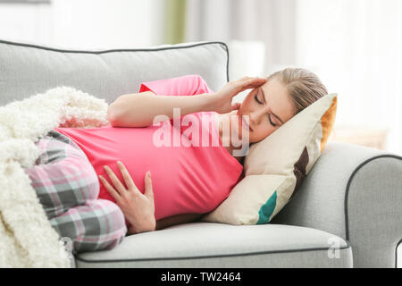 Schwangere Frau leidet unter Kopfschmerzen beim Liegen auf dem Sofa zu Hause Stockfoto
