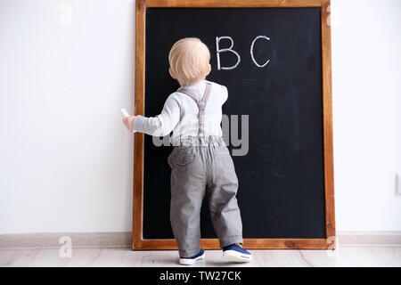 Cute little boy Schreiben auf Tafel im Klassenzimmer Stockfoto