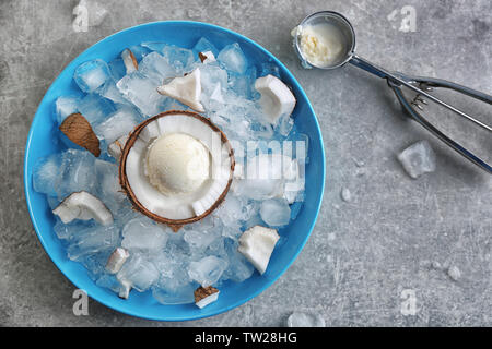 Die Hälfte der Kokosnuss mit frischem Eis Ball Kühlung auf eisigen Würfel in blaue Schale Stockfoto