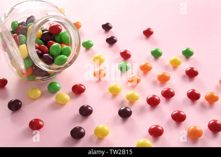 Leckere bunte Bonbons im Glas auf farbigen Hintergrund Stockfoto