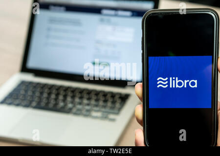 18. Juni 2019, Ljubljana, Slowenien - Hand mit einem Smartphone mit Waage Logo auf, neben Facebook Webseite geöffnet, die auf dem Computer Laptop Stockfoto