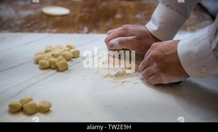 Ein taiwanesischer Chef rollt Teig vor dem Befüllen mit Fleisch zu Jiaozi erstellen, eine chinesische Knödel. Asiatischer Mann frische Knödel in einer Küche Stockfoto
