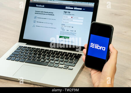 18. Juni 2019, Ljubljana, Slowenien - Hand mit einem Smartphone mit Waage Logo auf, neben Facebook Webseite geöffnet, die auf dem Computer Laptop Stockfoto