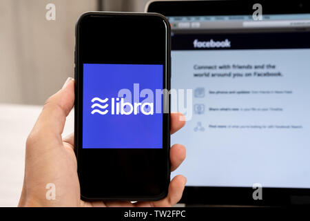 18. Juni 2019, Ljubljana, Slowenien - Hand mit einem Smartphone mit Waage Logo auf, neben Facebook Webseite geöffnet, die auf dem Computer Laptop Stockfoto