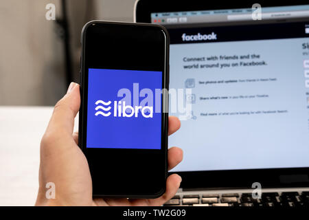 18. Juni 2019, Ljubljana, Slowenien - Hand mit einem Smartphone mit Waage Logo auf, neben Facebook Webseite geöffnet, die auf dem Computer Laptop Stockfoto