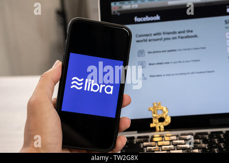 18. Juni 2019, Ljubljana, Slowenien - Hand mit einem Smartphone mit Waage Logo auf, neben Facebook Webseite geöffnet, die auf dem Computer Laptop Stockfoto