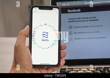 18. Juni 2019, Ljubljana, Slowenien - Hand mit einem Smartphone mit Waage Logo und der Waage Partner, neben Facebook Website eröffnet am Laptop Stockfoto