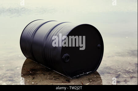 Big Black Barrel am Strand. Umweltverschmutzung Konzept Stockfoto