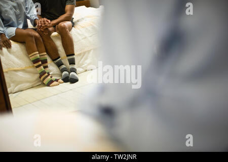 Junges Paar in die passende Socken sitzen auf den Rand des Bettes. Stockfoto