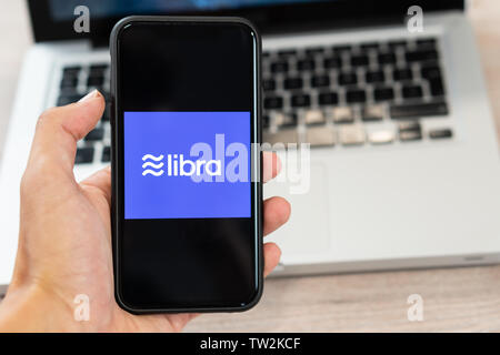 18. Juni 2019, Ljubljana, Slowenien - Hand mit einem Smartphone mit Waage Logo auf, neben dem Laptop. Facebook Neue cryptocurrency für Transaktionen Stockfoto