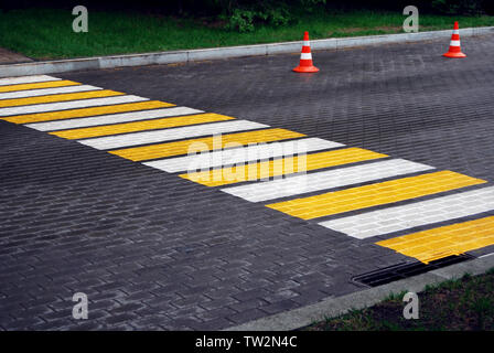 Fußgängerampel und Leitkegel auf einer gepflasterten Straße an regnerischen Tag Stockfoto