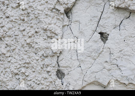 Extrem rauen grungy Textur von weiß verputzten Stein an der Wand, halb zerstört, angebrochen und rissig Stockfoto