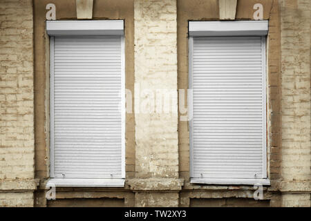 Weiße Fenster mit geschlossenen Rollläden in der Wand Stockfoto