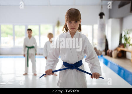 Kimono und Gürtel. Cute ansprechende Schulmädchen mit weissen Kimono und Blue Belt in ernsten Gesicht Stockfoto