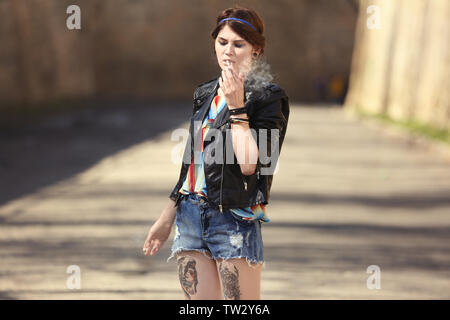 Schöne junge Frau Gras rauchen im Freien Stockfoto