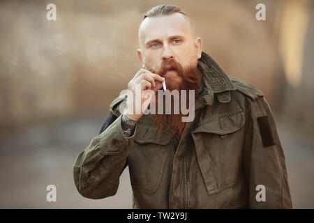 Bärtiger Mann Gras rauchen im Freien Stockfoto