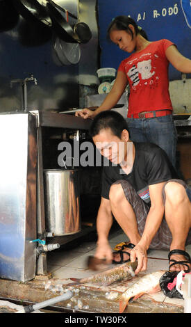 Vietnamesische erwachsenen Mann und Junge arbeiten wie ein Fisch Metzger auf einem Hauptgeschäft in einem offenen Markt aufschneiden und den Verkauf von Fisch bei Stadt Hanoi Vietnam, Asien Stockfoto