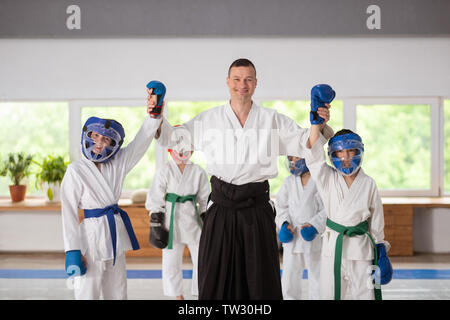 Strahlende Sieger. Strahlende Trainer heben die Hände der Gewinner nach Boxkämpfe und Üben von Martial Arts Stockfoto