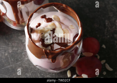 Leckeren Joghurt Parfait mit Schokoladensauce und Mandel Blütenblätter im Glas auf dem Tisch Stockfoto