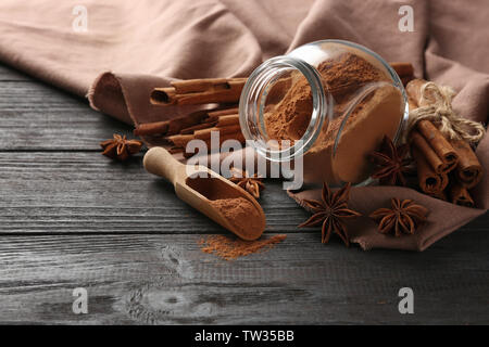 Glas Glas mit zimtpulver und Anis Sterne auf hölzernen Tisch Stockfoto