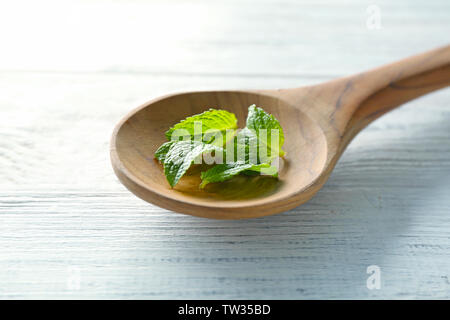 Löffel aus Holz mit Blätter der Zitronenmelisse auf Tisch Stockfoto