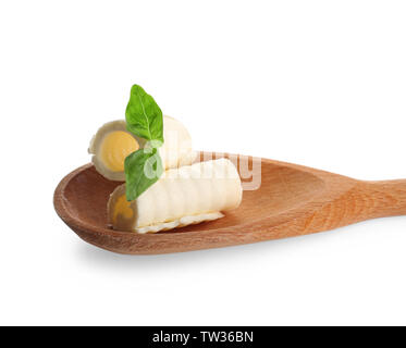 Köstliche butter Locken und Basilikumblätter in hölzernen Löffel auf weißem Hintergrund, Nahaufnahme Stockfoto