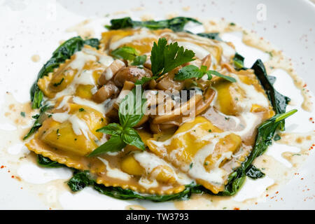 Nahaufnahme von Frische hausgemachte Porcini-pilzen gefüllte Ravioli mit Spinat, Butter und Parmesan Creme mit grünem Basilikum und aromatischen Kräutern Isola Stockfoto