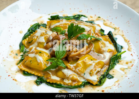 Nahaufnahme von Frische hausgemachte Porcini-pilzen gefüllte Ravioli mit Spinat, Butter und Parmesan Creme mit grünem Basilikum und aromatischen Kräutern Isola Stockfoto