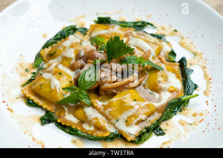 Nahaufnahme von Frische hausgemachte Porcini-pilzen gefüllte Ravioli mit Spinat, Butter und Parmesan Creme mit grünem Basilikum und aromatischen Kräutern Isola Stockfoto