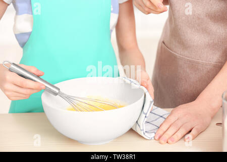 Mutter und Tochter Schlagsahne Eier in der Schale auf dem Küchentisch Stockfoto